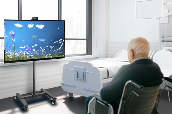 Compassionate-dementia-care-technology image of elderly man in wheelchair watching large screen