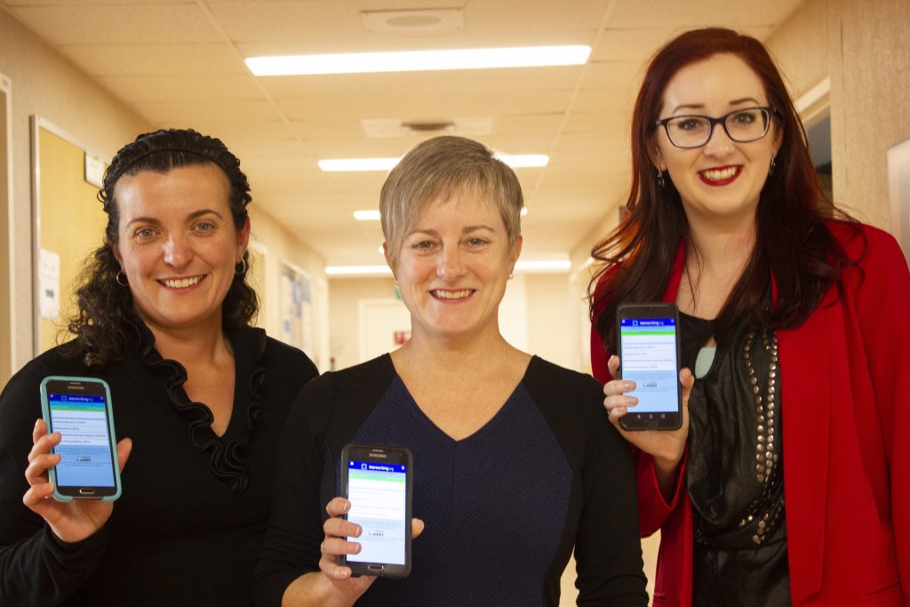 The project lead Barbara Farrell and the project team hold up smartphones