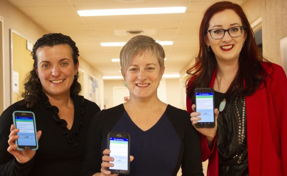 The project lead Barbara Farrell and the project team hold up smartphones