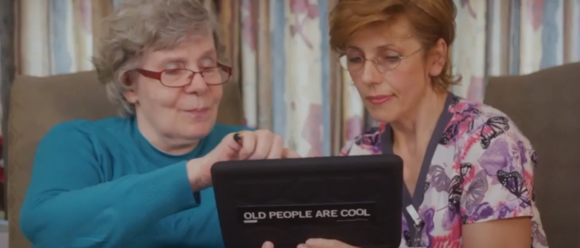 Older adult woman and a female nurse look at a tablet together.