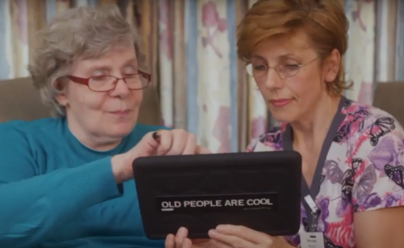 Older adult woman and a female nurse look at a tablet together.