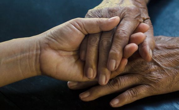 An older woman's hands are held.