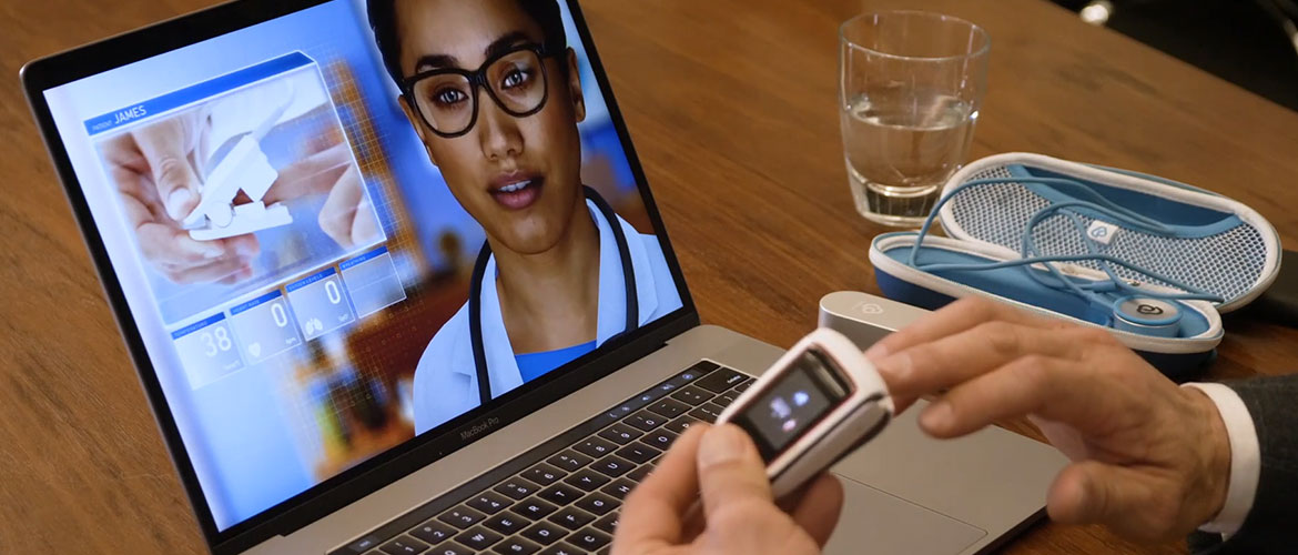 An artificial human is shown on a laptop screen while a person uses an oximeter.
