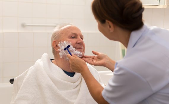 Caregiver helping a senior man with grooming