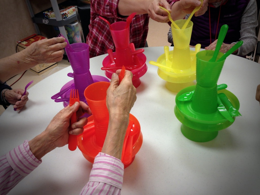 A photo showing the hands of seniors, who are playing with plastic cutlery 