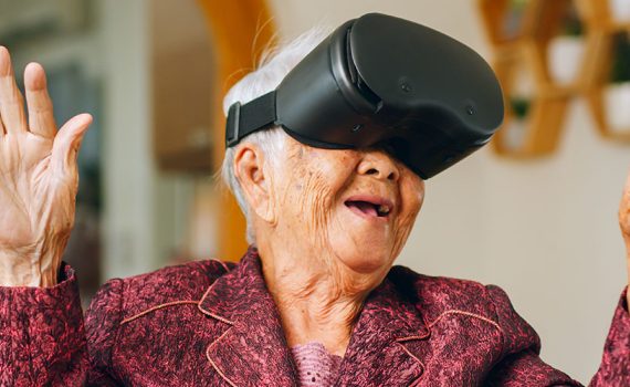 Older woman wearing a VR headset at home. Hands are up. Face in awe.