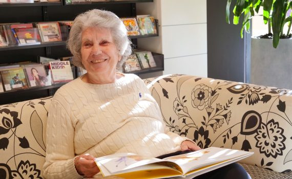 A smiling senior woman with a book opened on her lap