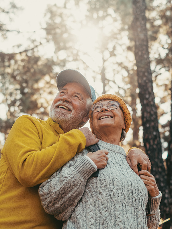 senior outdoorsy couple look up in a forest, smiling