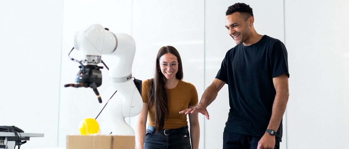 A man and a woman playing with a robot.